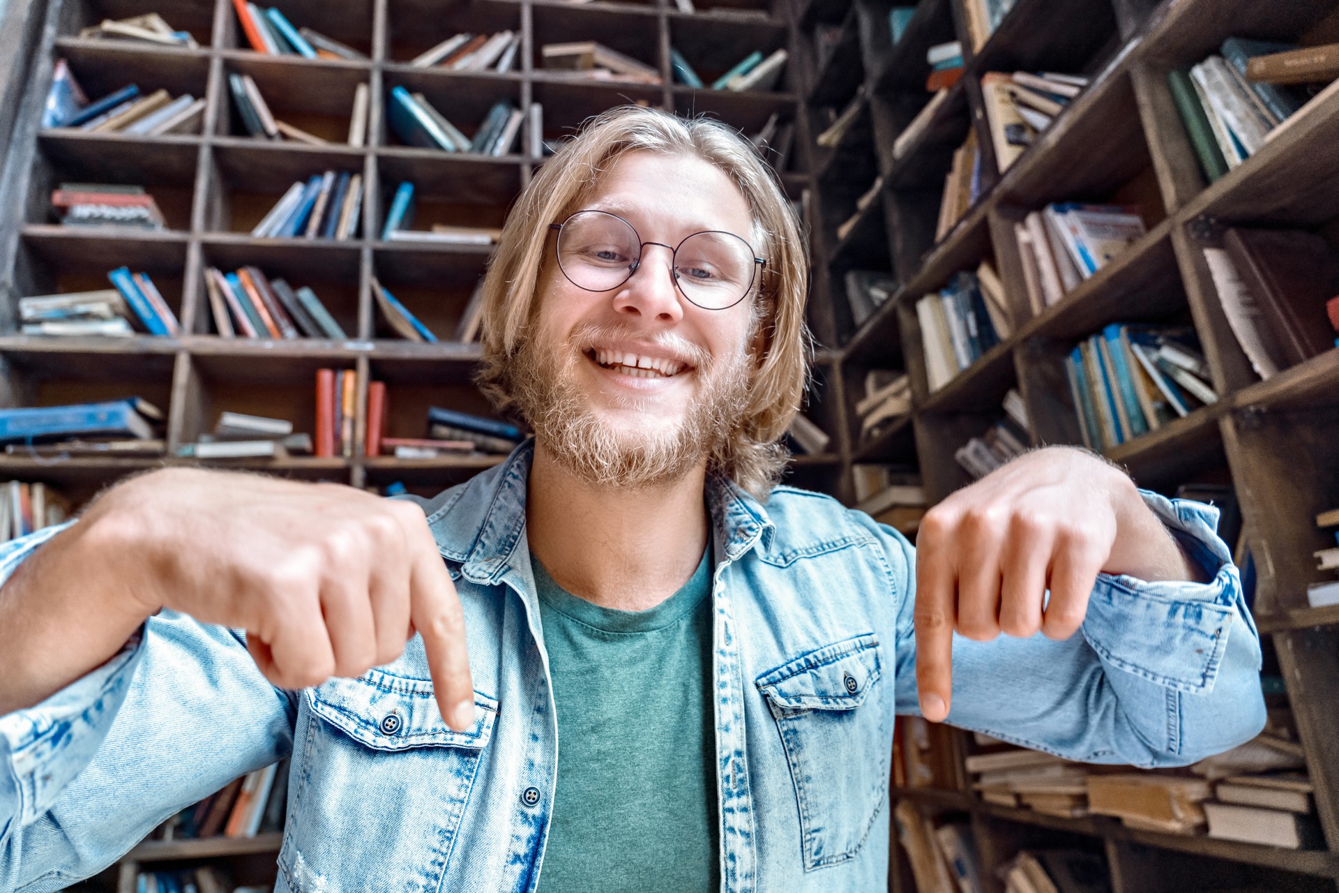 Happy male blogger influencer looking at camera pointing on subscription recording video blog concept in library, happy young man shoot vlog for social media channel ask followers to subcribe concept